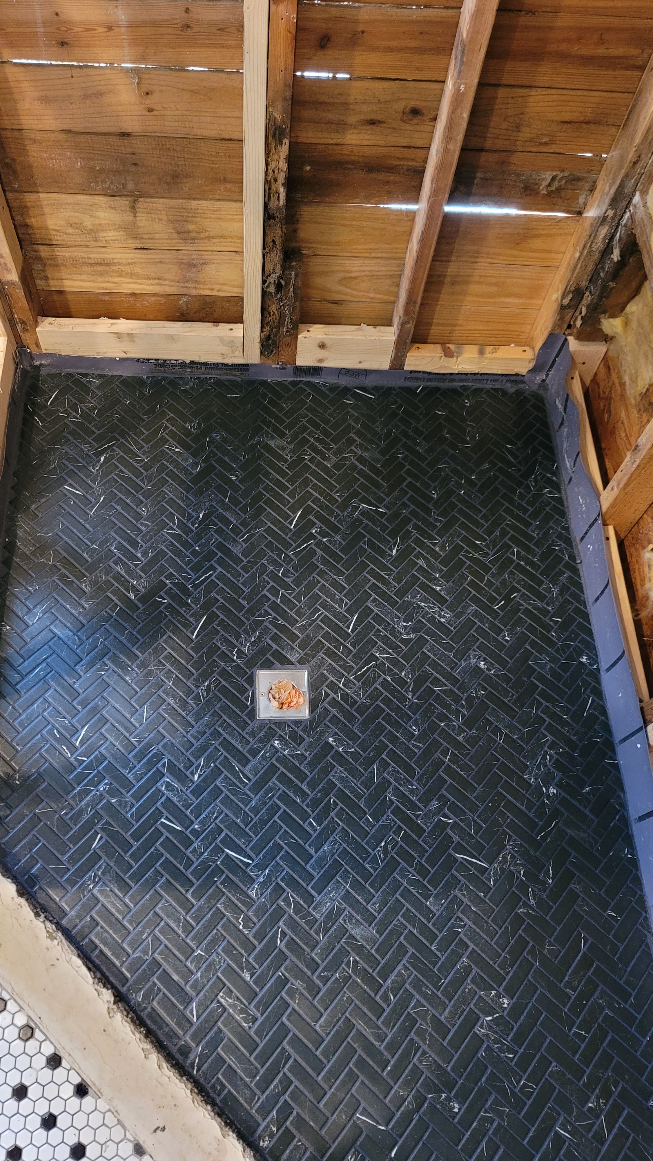 Dark herringbone tile laid between floor framing