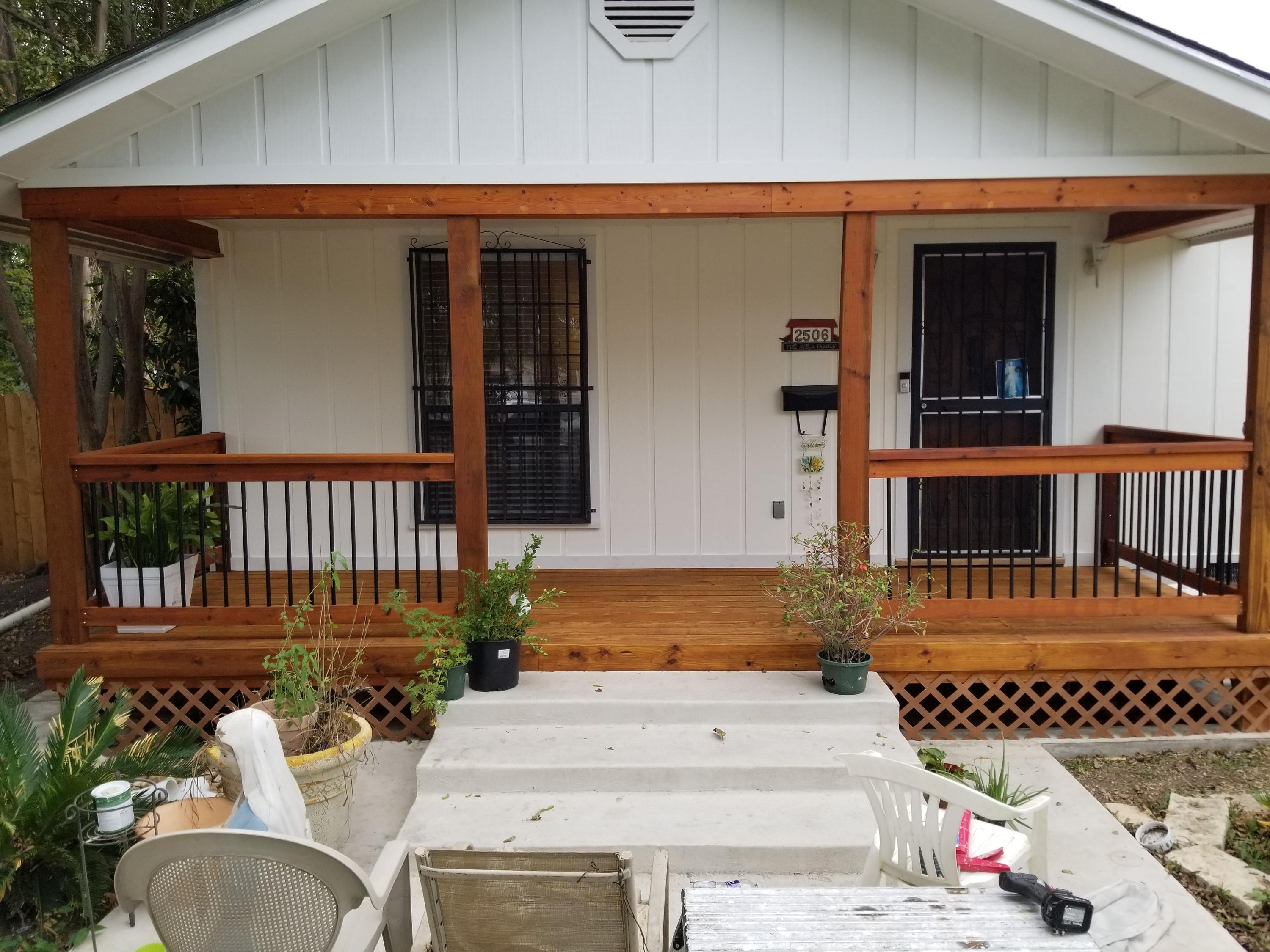 Front porch with wood posts, metal railing and concrete steps