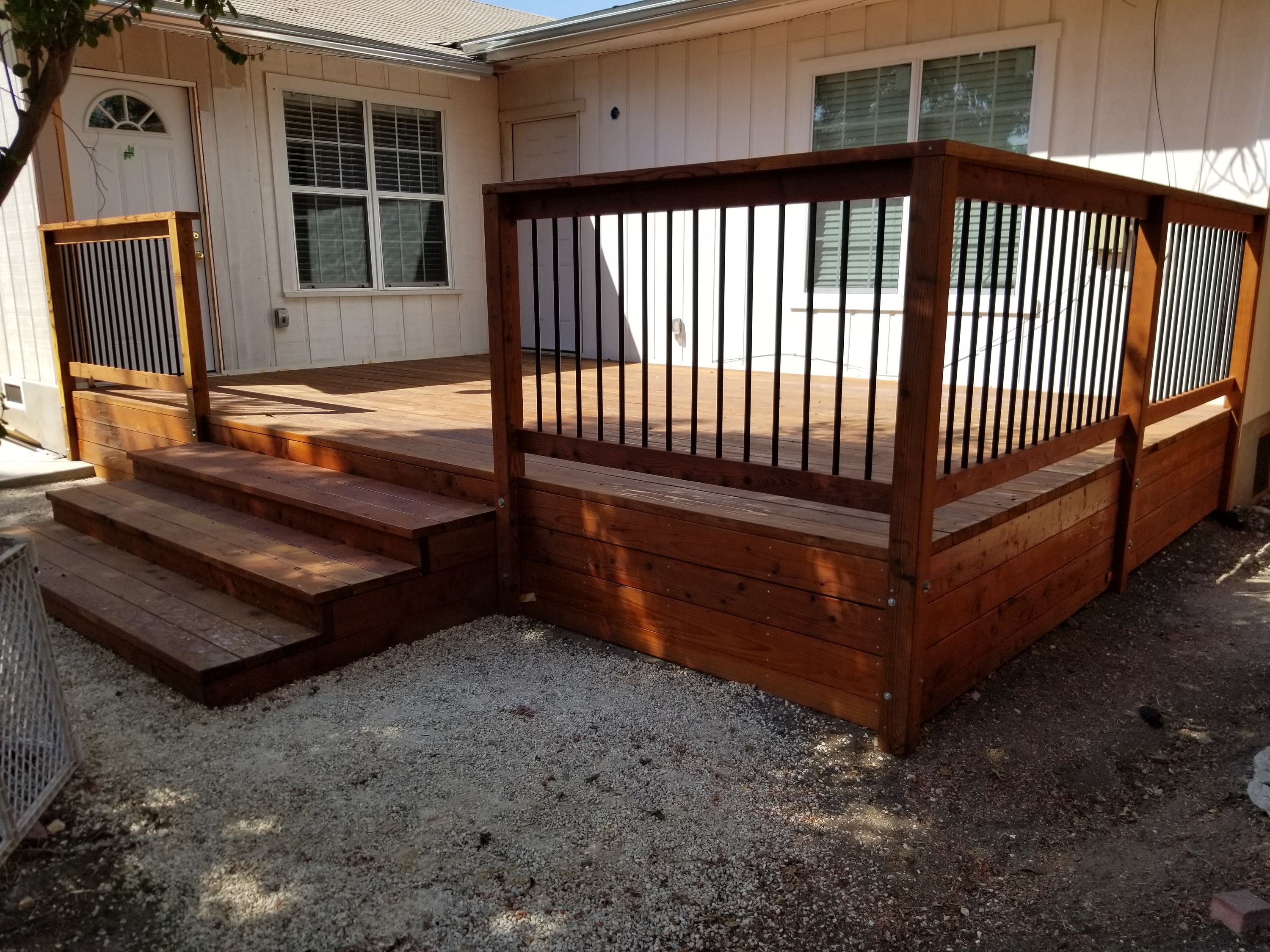 Redwood deck with dark metal balusters and steps down to gravel
