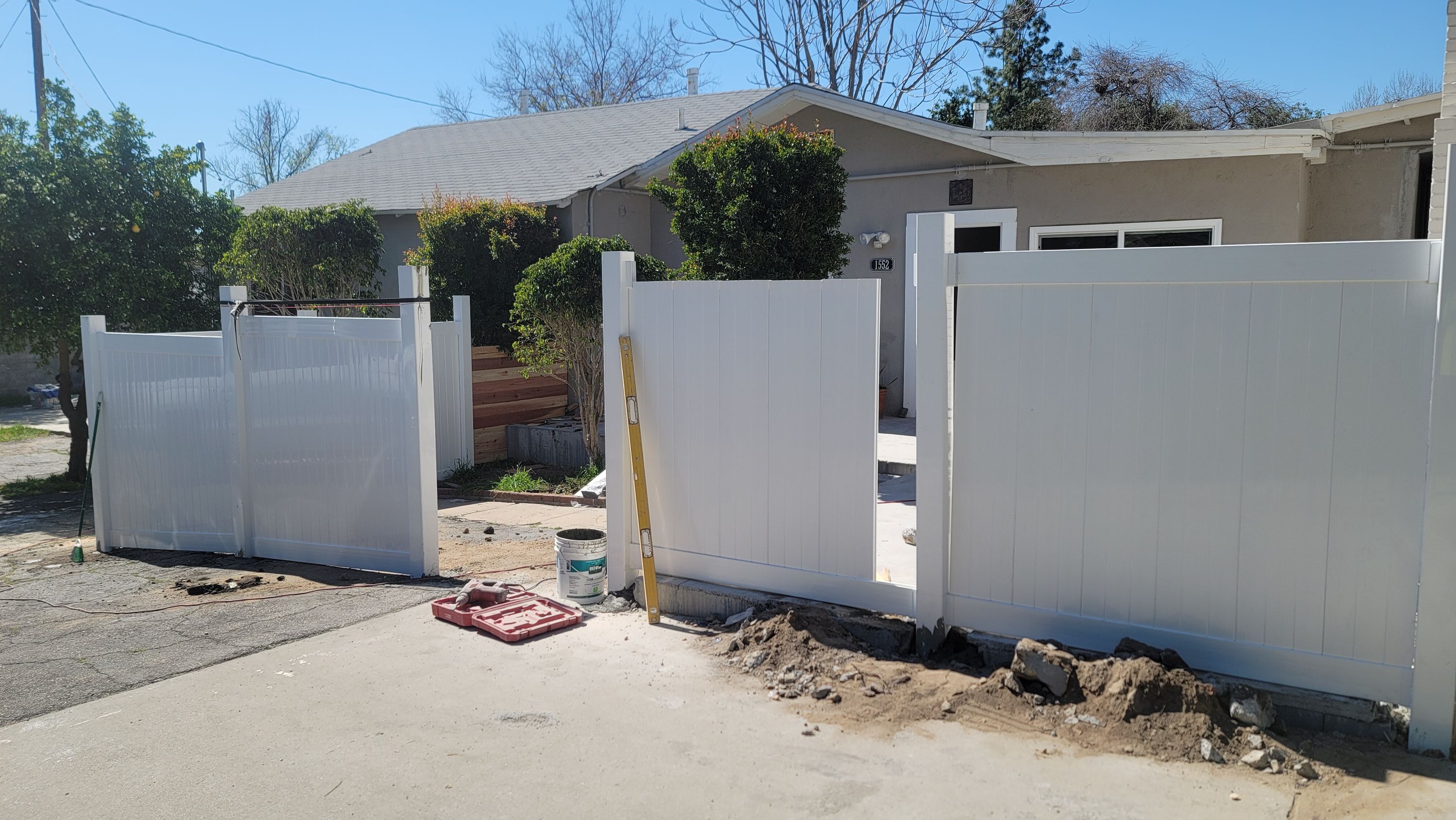 White vinyl fence posts being set in a front yard