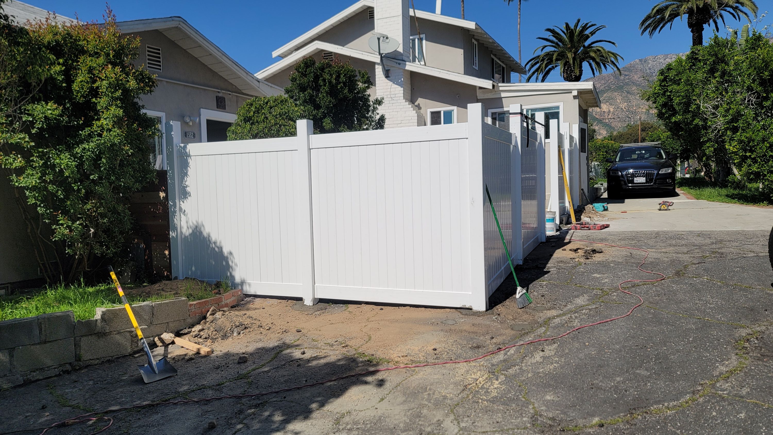 New white vinyl fence panels installed alongside a driveway
