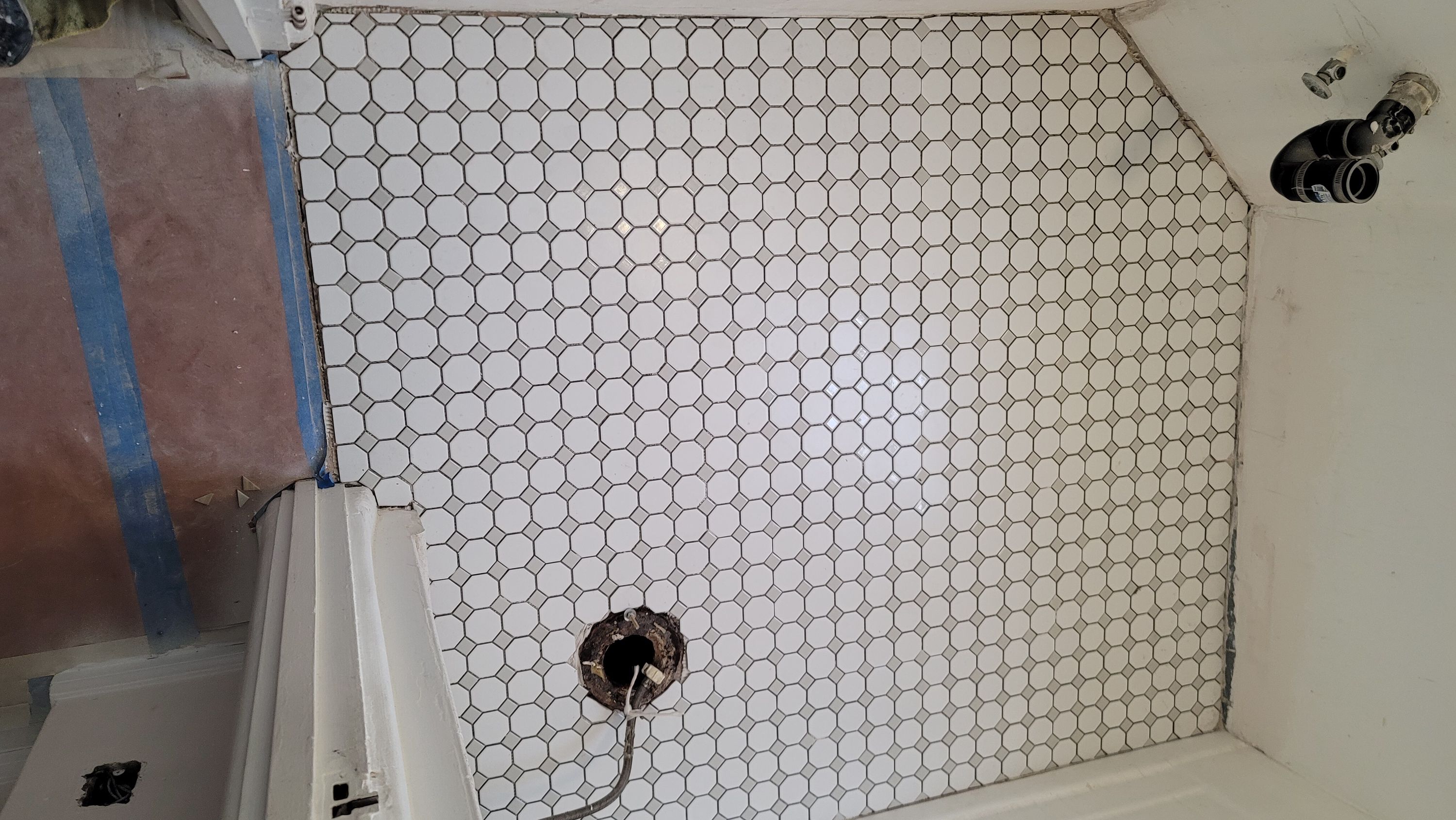 White hexagon tile wall with a plumbing stub-out