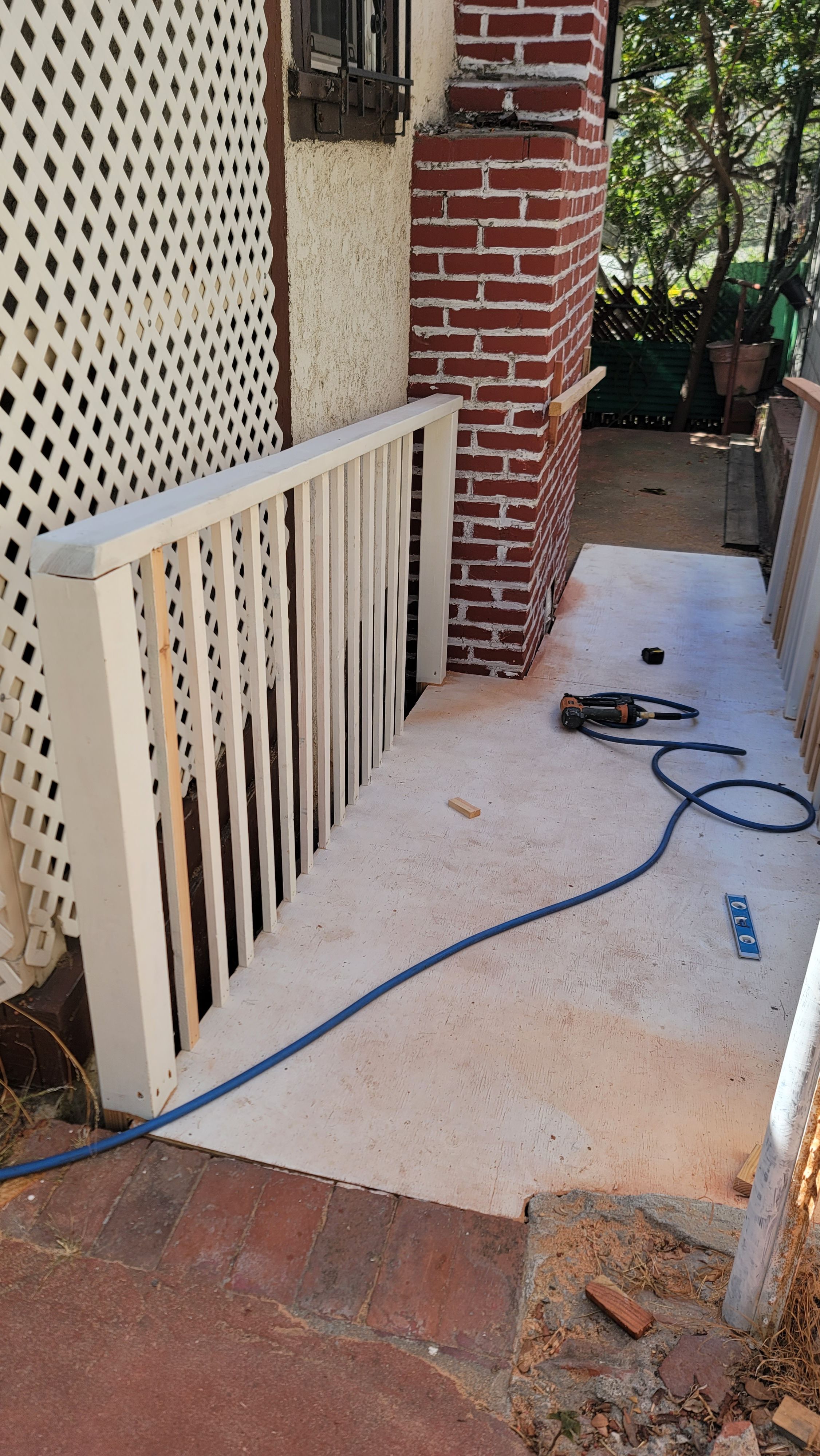 Bare concrete side walkway before coating, with railing and lattice