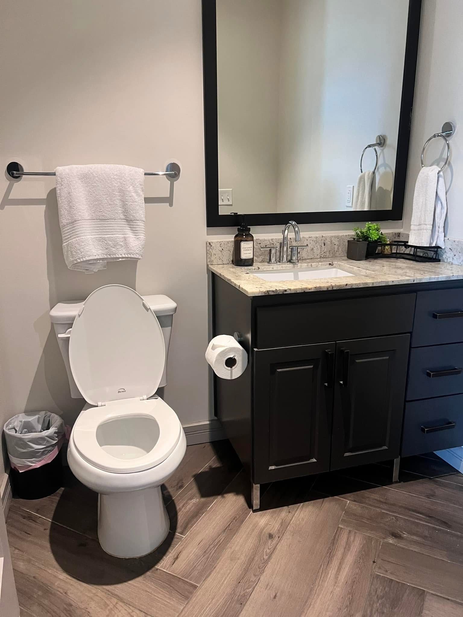 Sanitized bathroom with clean toilet, vanity, mirror, and folded towels