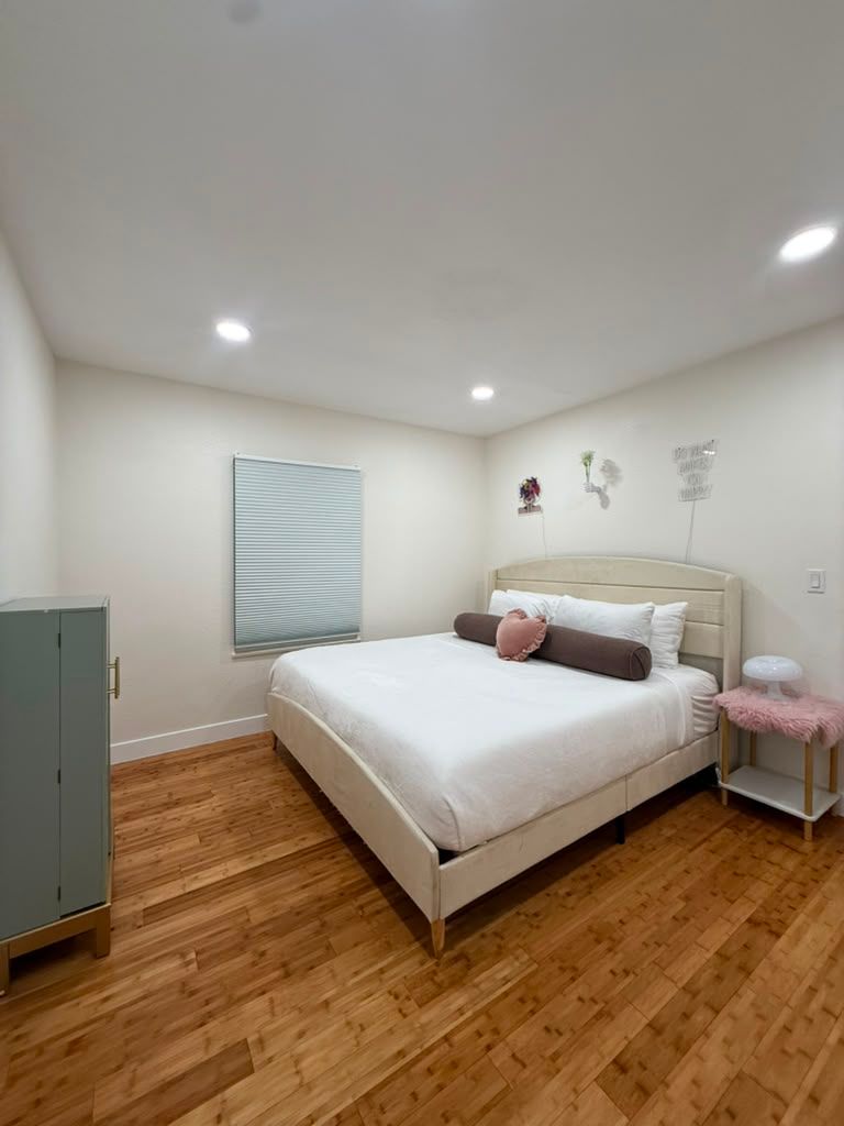 Bedroom with a made bed and wood floor