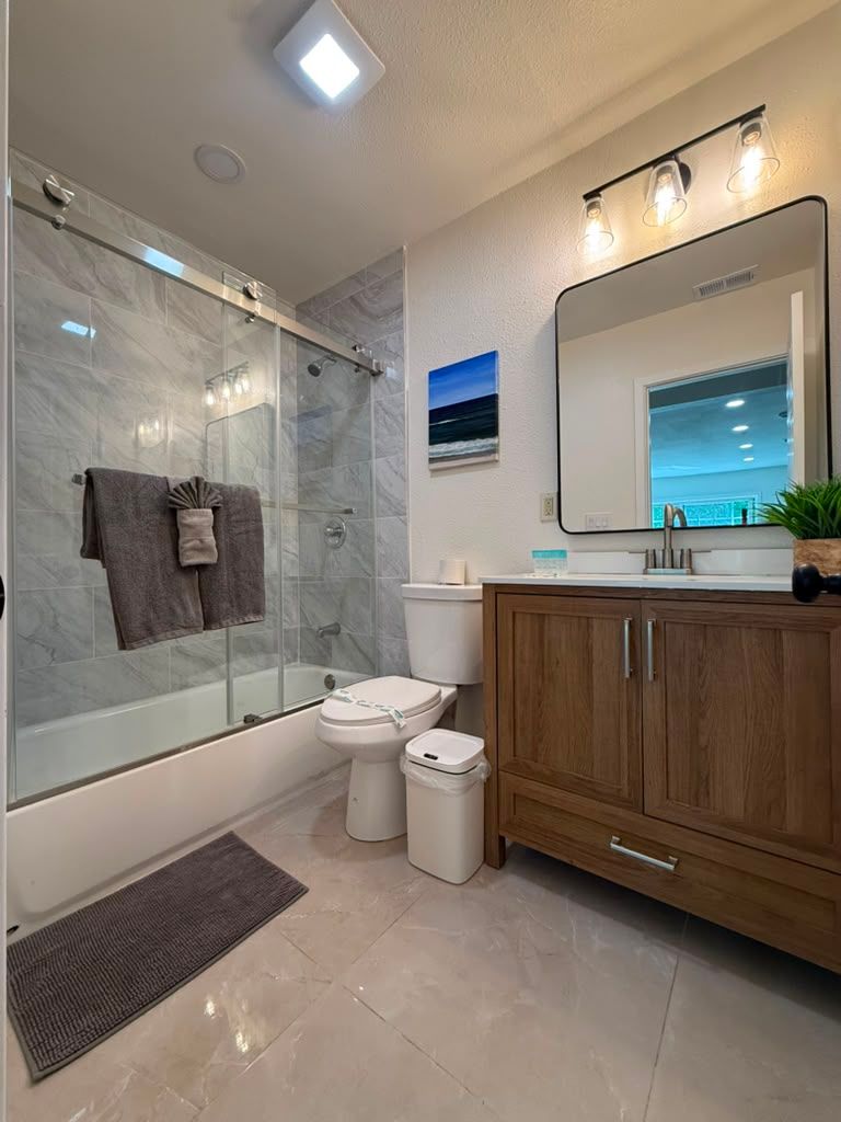 Bathroom with marble-look tile shower and wood vanity