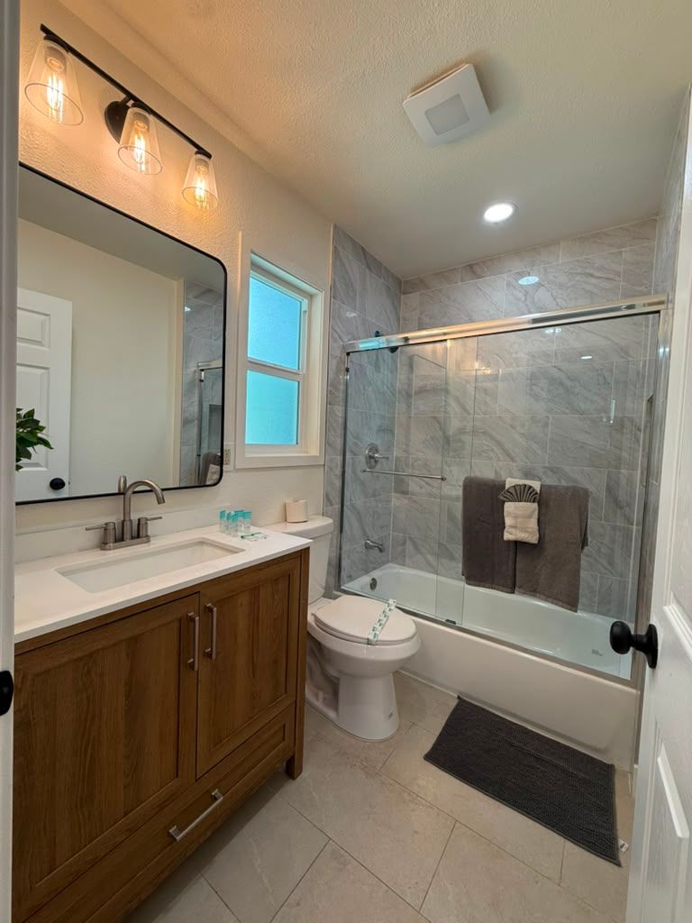 Bathroom with a wood vanity, glass shower door and folded towels