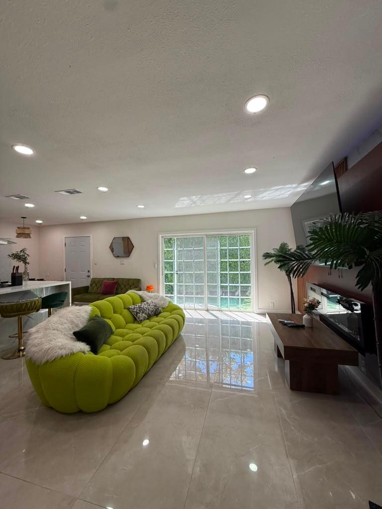 Open-plan living room with a lime green sofa and polished tile floor