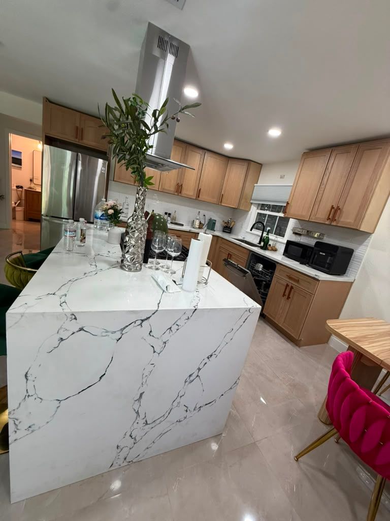 Marble waterfall island in a kitchen with wood cabinets