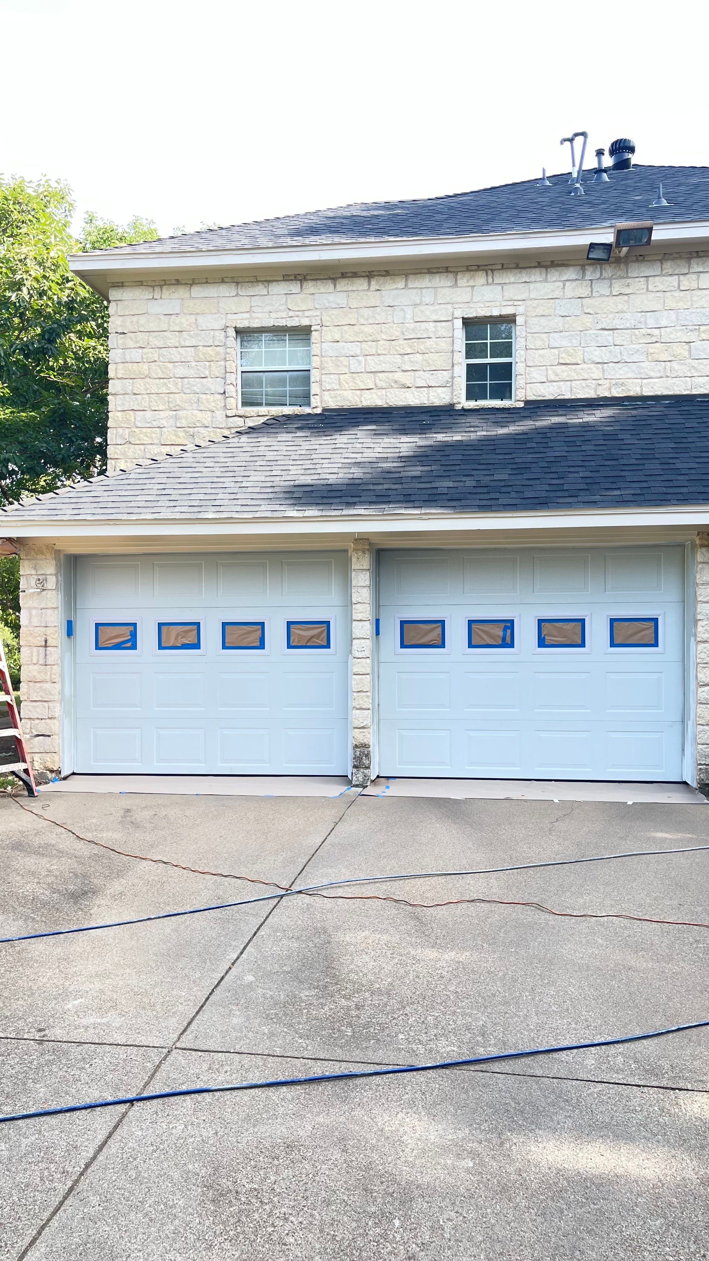 A pair of garage doors masked off with tape and paper during an exterior repaint by JC Painting Services