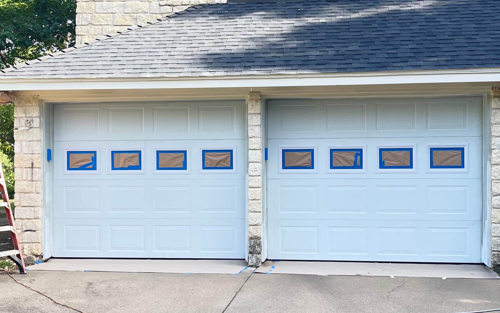 A pair of garage doors masked off with tape and paper during an exterior repaint by JC Painting Services