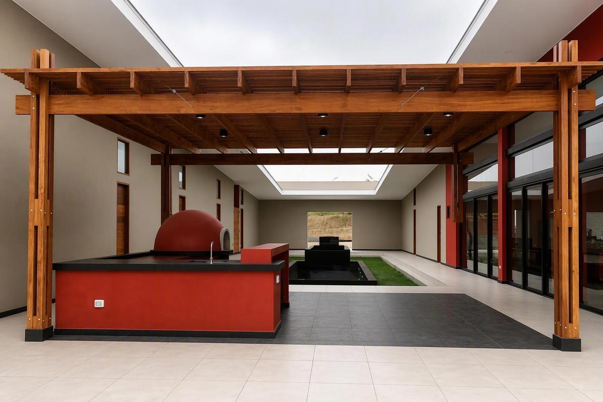 Outdoor kitchen under a timber pergola with tiled floor and water feature, completed by JCH Projects & Investments
