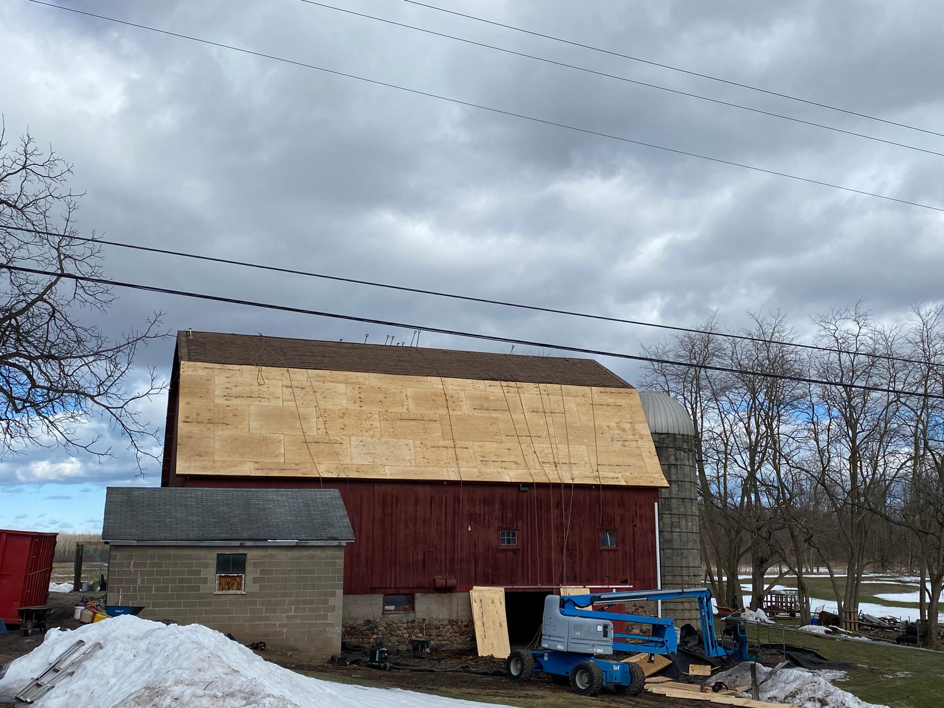Juarez Home Improvements crew re-sheathing a red barn roof in Orleans County, NY