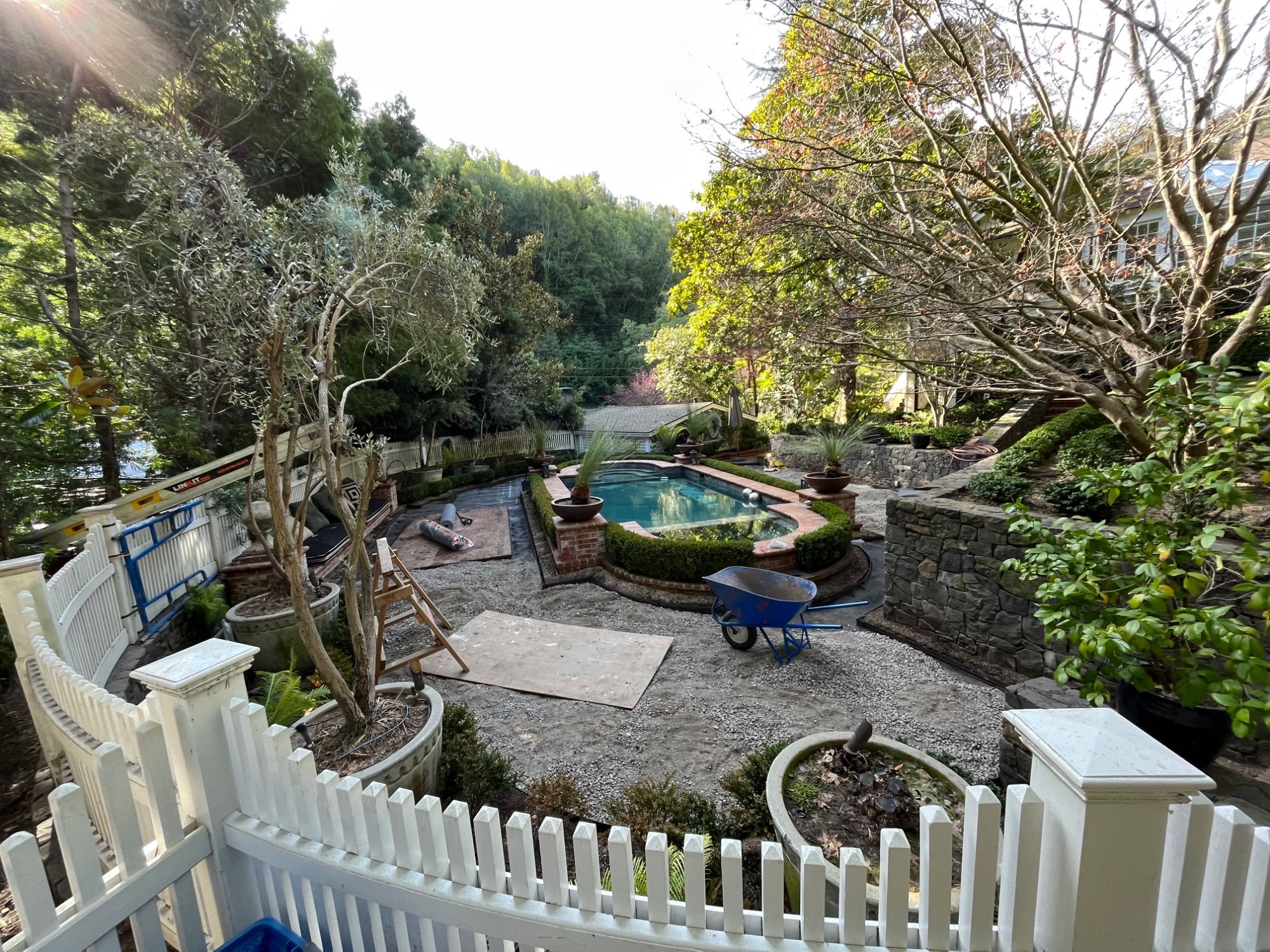 A hillside pool terrace part way through construction, with gravel and stonework in progress