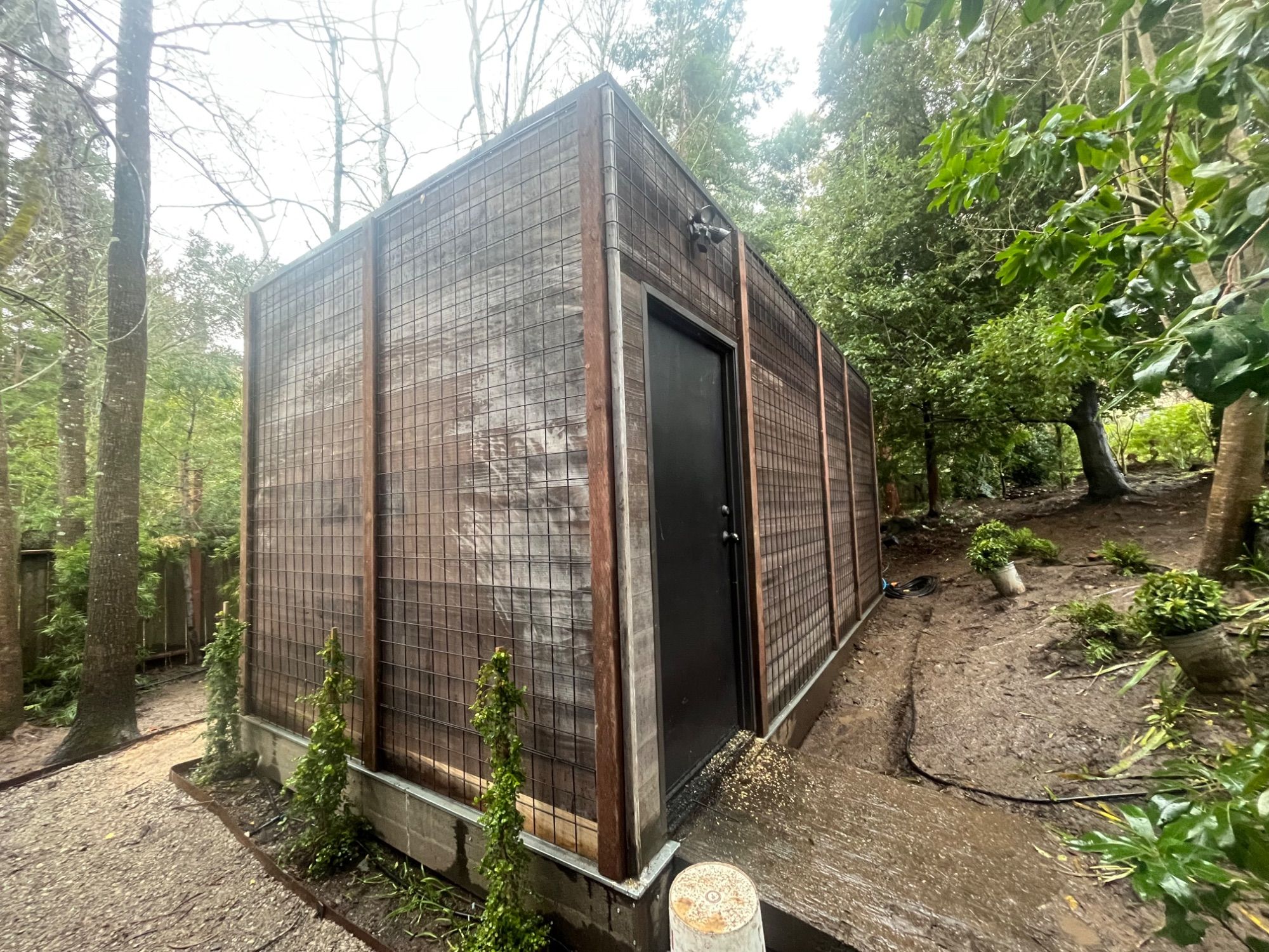 A slatted hardwood screen enclosure built on a wooded lot