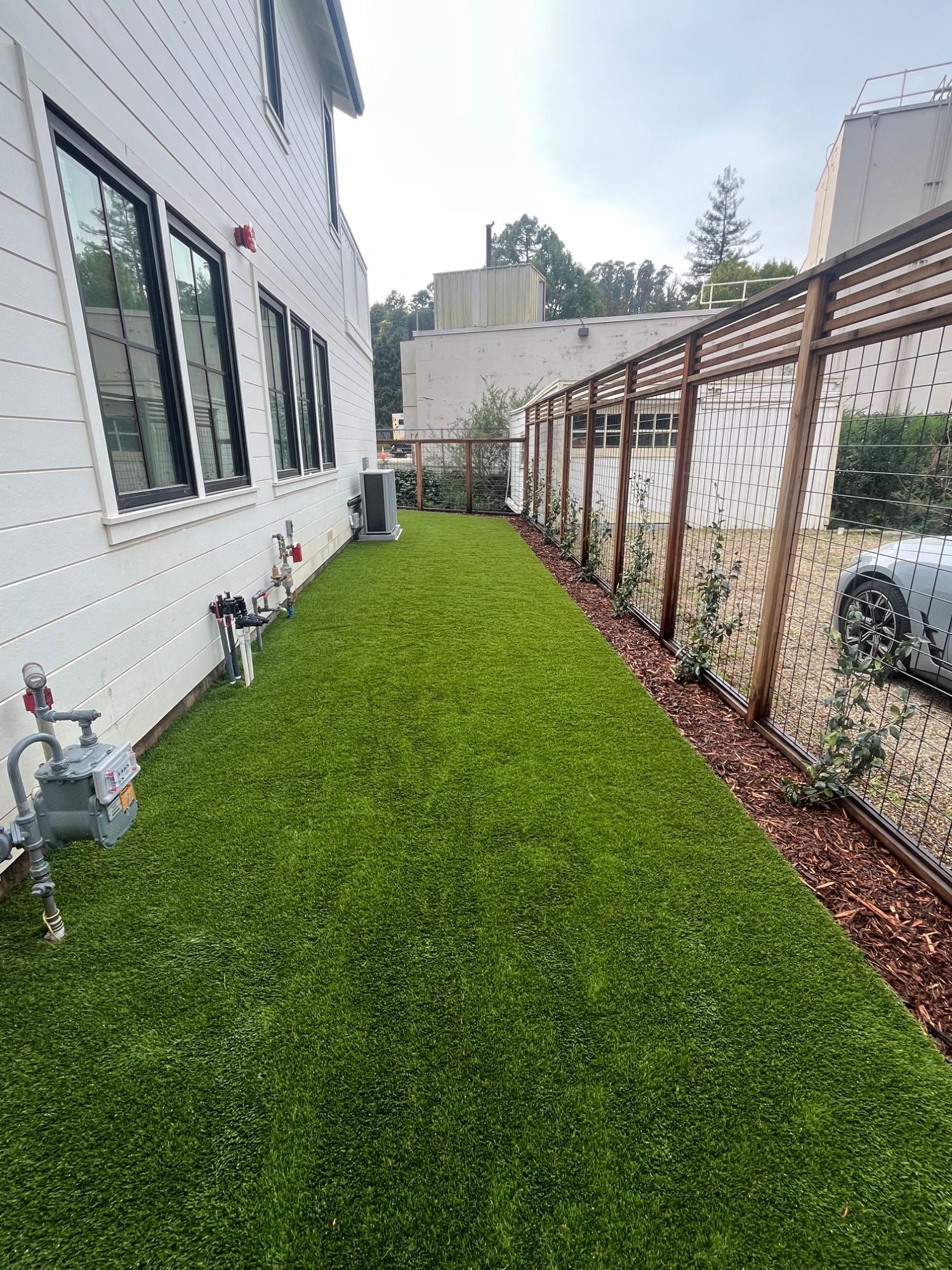 Artificial turf laid down a narrow side yard beside a white clapboard house