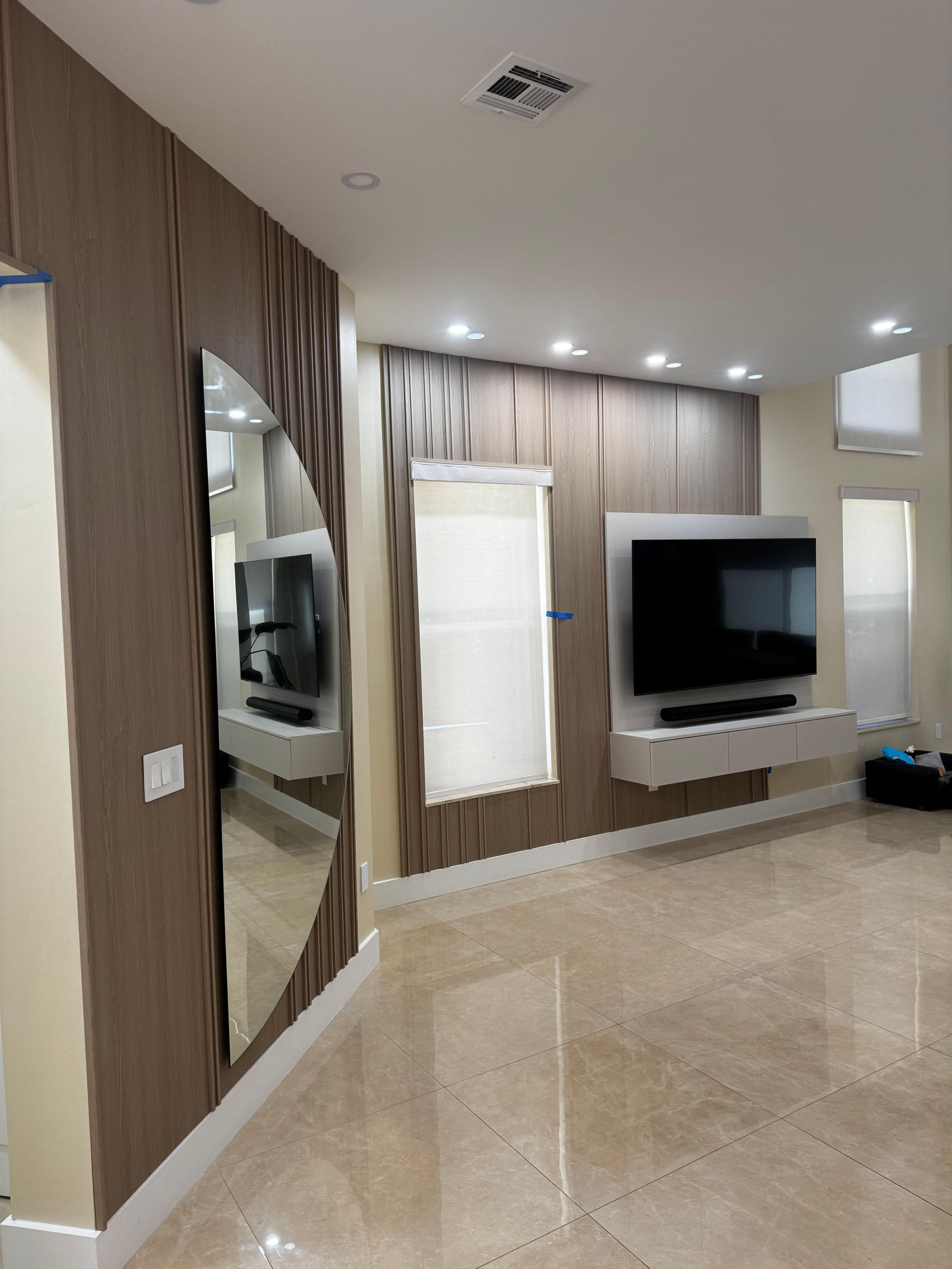 Fluted walnut wall paneling with floating TV console and full-height arched mirror