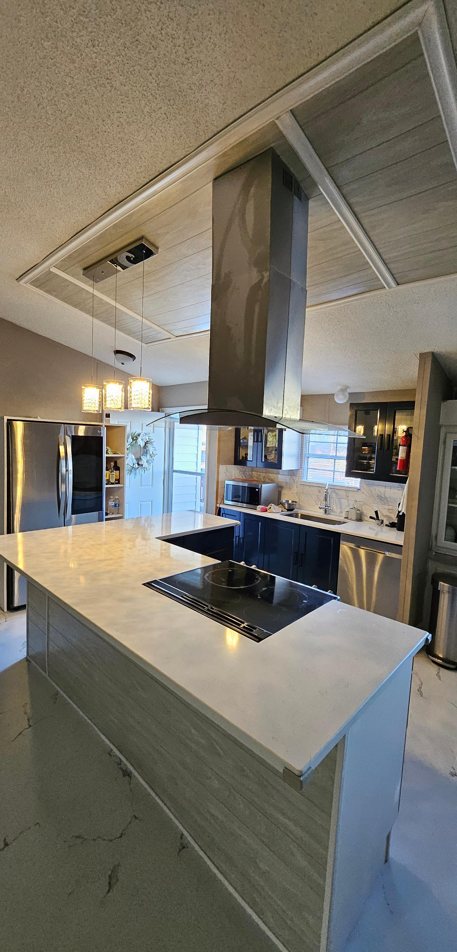 Remodeled kitchen with a quartz island and stainless range hood by New Generation Home Improvement in Charlotte