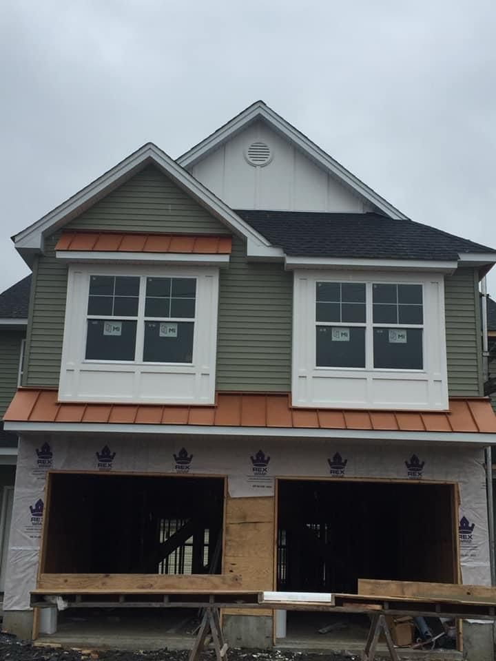 Two-storey home with new siding, copper-tone metal roofing accents and white window surrounds — NYE General Construction