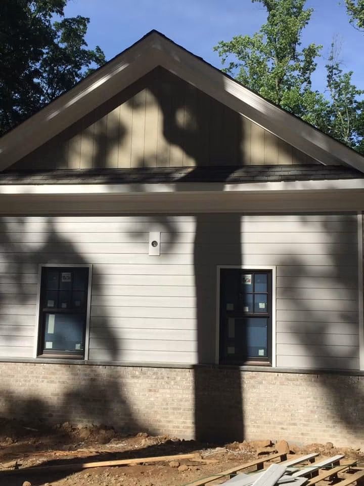 New lap siding and board-and-batten gable over a brick base, windows trimmed out — NYE General Construction