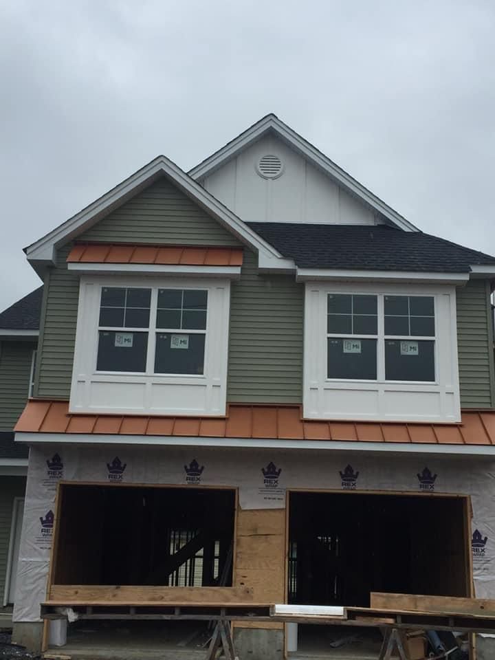 Front elevation with new lap siding, standing-seam metal roof accents and finished window trim — NYE General Construction