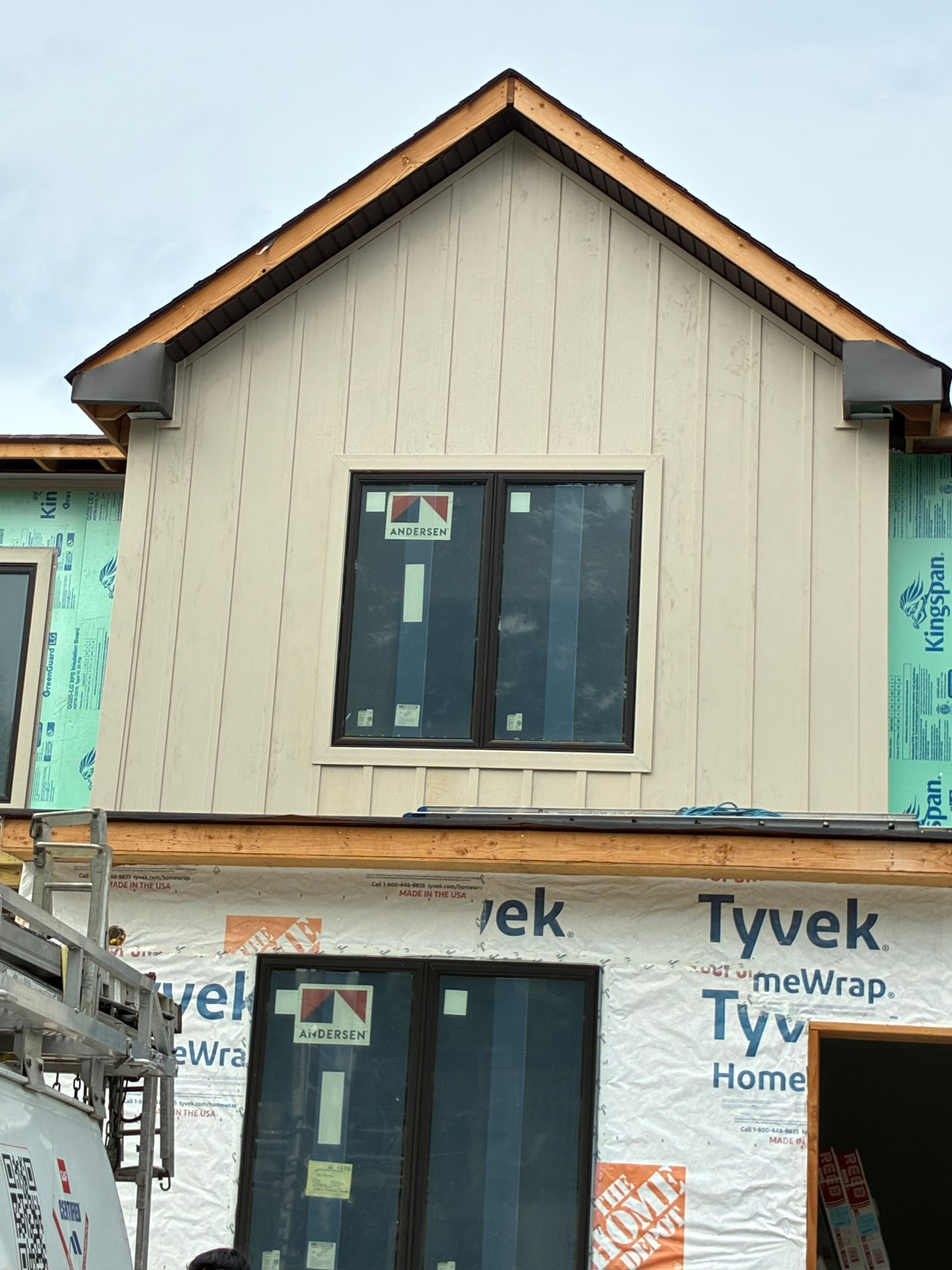 Board-and-batten gable siding and new wood trim around black-frame windows — NYE General Construction