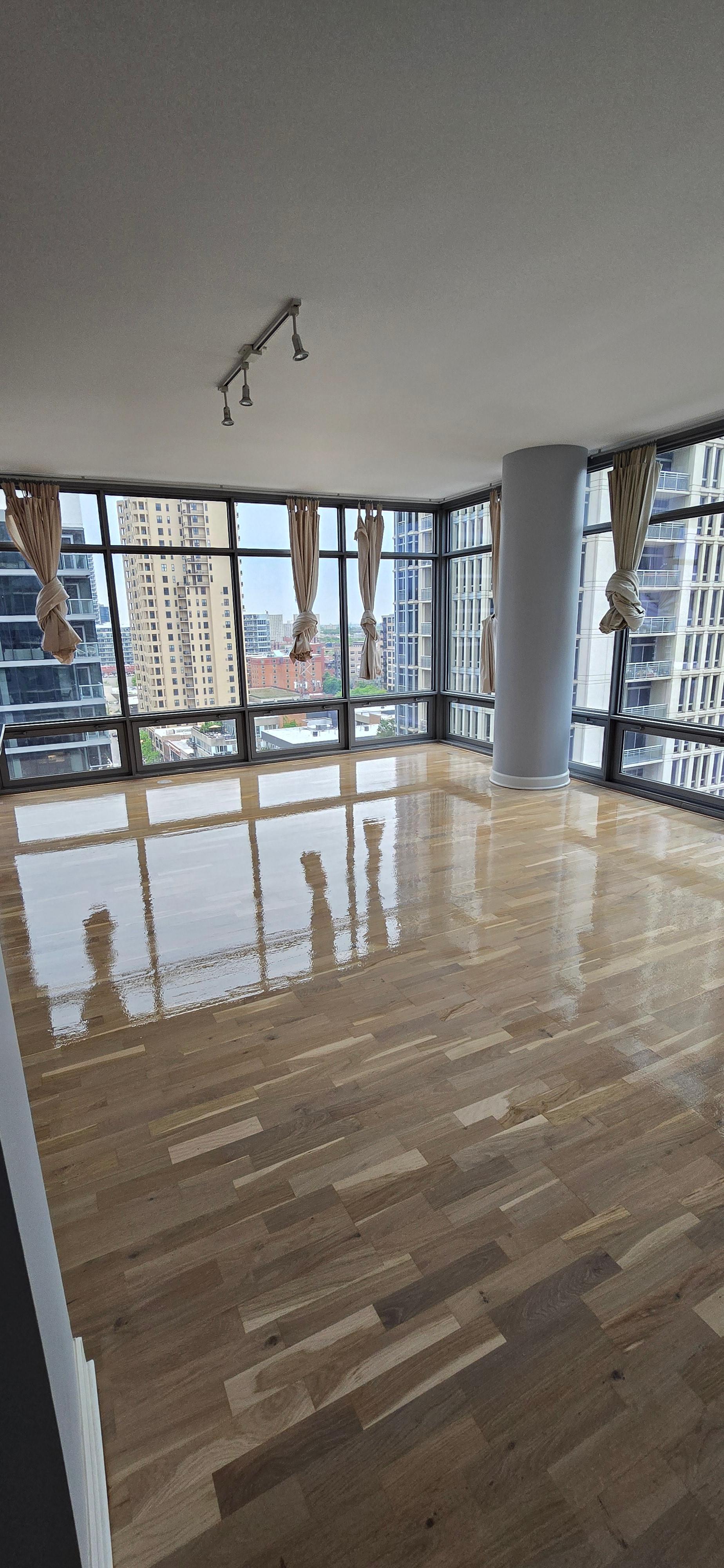High-gloss hardwood floor refinished by One Star Flooring in a Chicago high-rise with skyline views