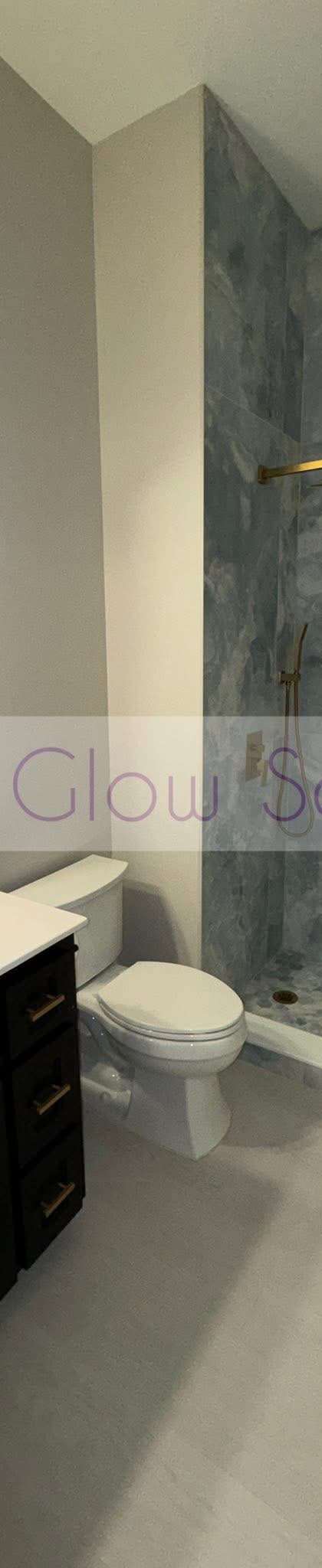 Spotless bathroom with a marble-look shower surround and gold fixtures cleaned by Purple Glow Services