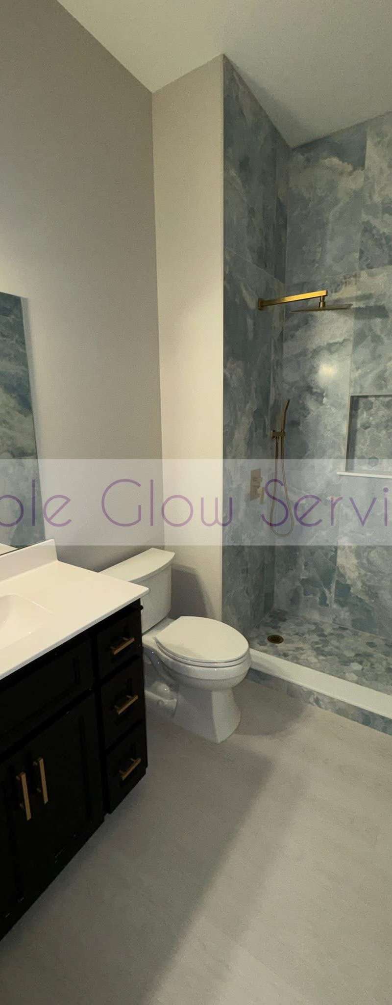 Spotless bathroom with a marble-look shower surround and gold fixtures cleaned by Purple Glow Services