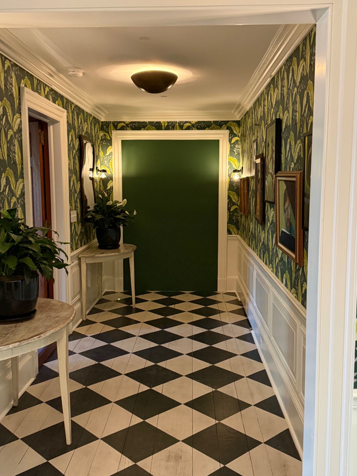 Hallway painted by Soto Painting Corporation — deep green accent wall, white wainscoting and trim, checkerboard floor