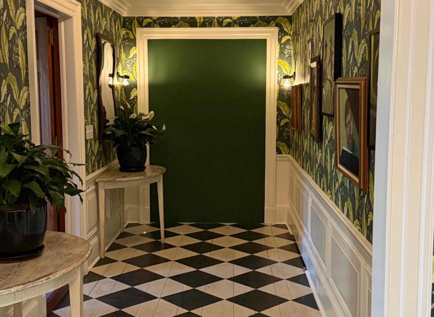 Hallway painted by Soto Painting Corporation — deep green accent wall, white wainscoting and trim, checkerboard floor
