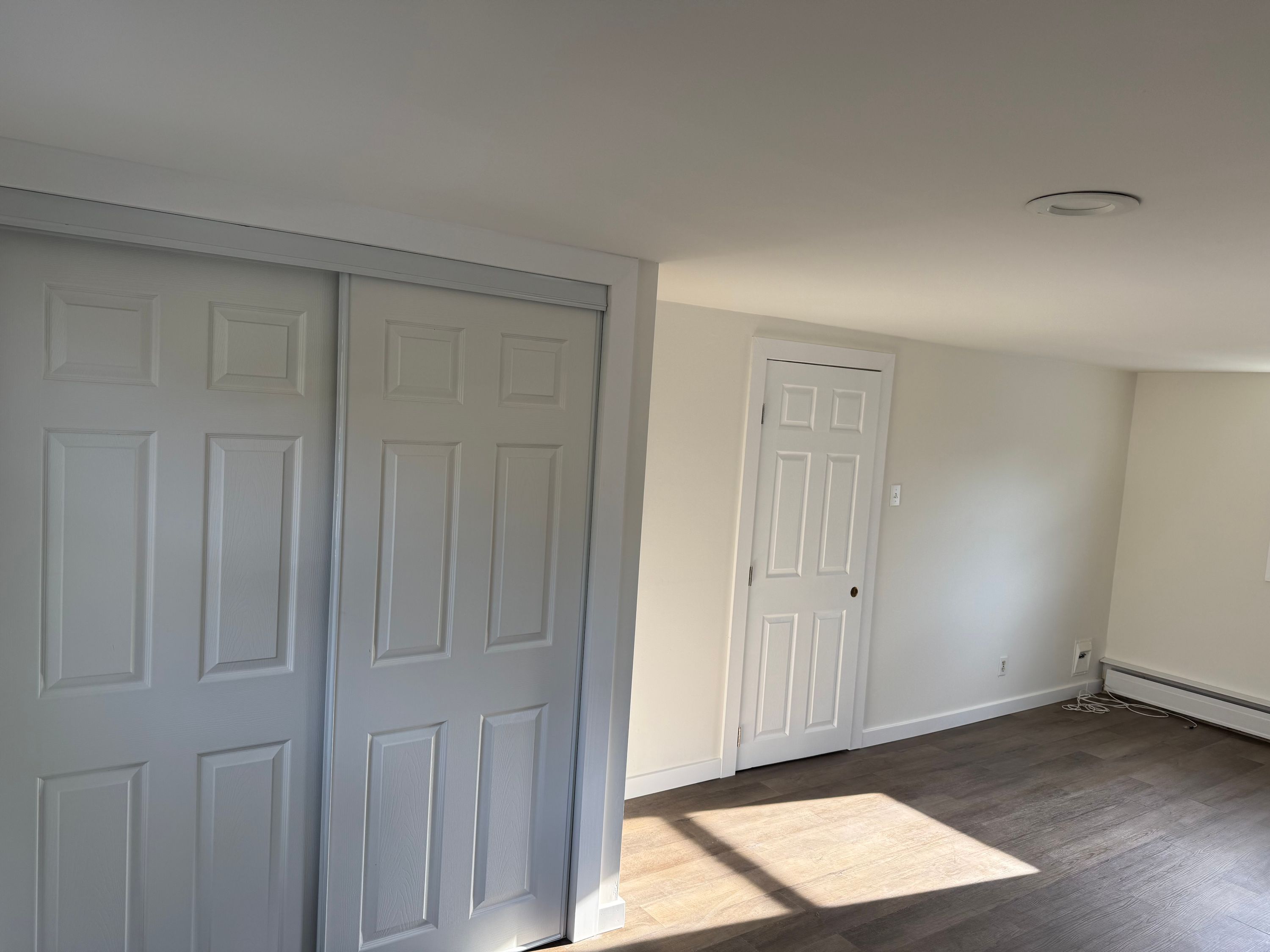 Freshly painted room by Soto Painting Corporation with new sliding closet doors and plank flooring