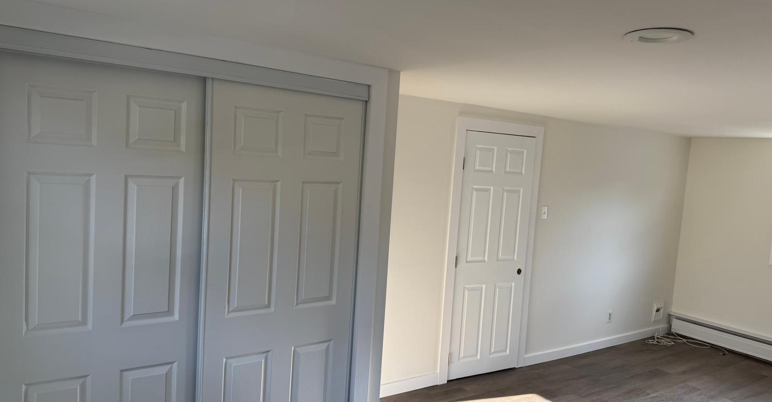 Freshly painted room by Soto Painting Corporation with new sliding closet doors and plank flooring