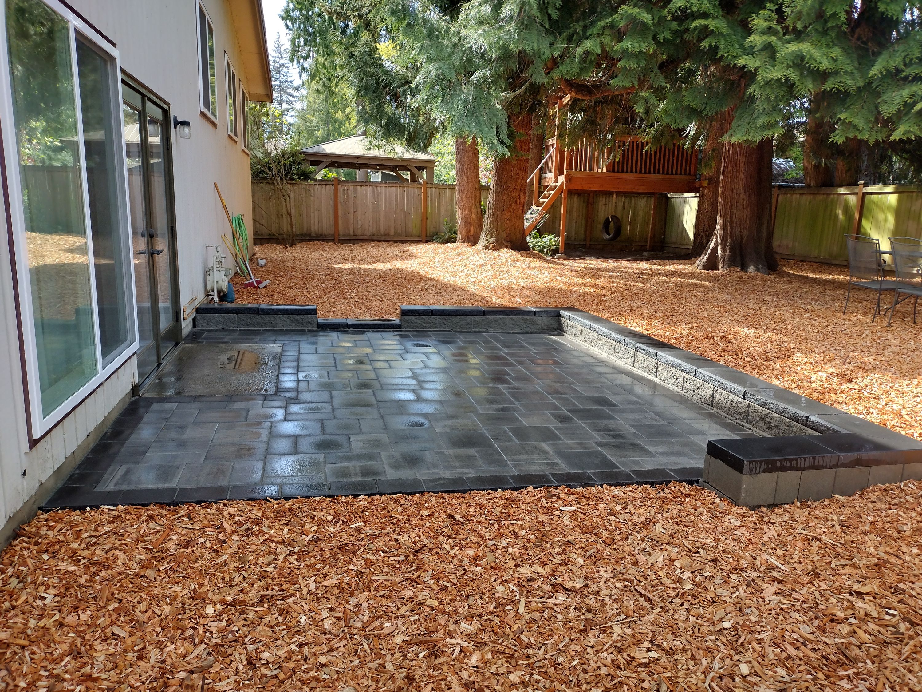 Finished paver patio with block retaining wall and fresh bark