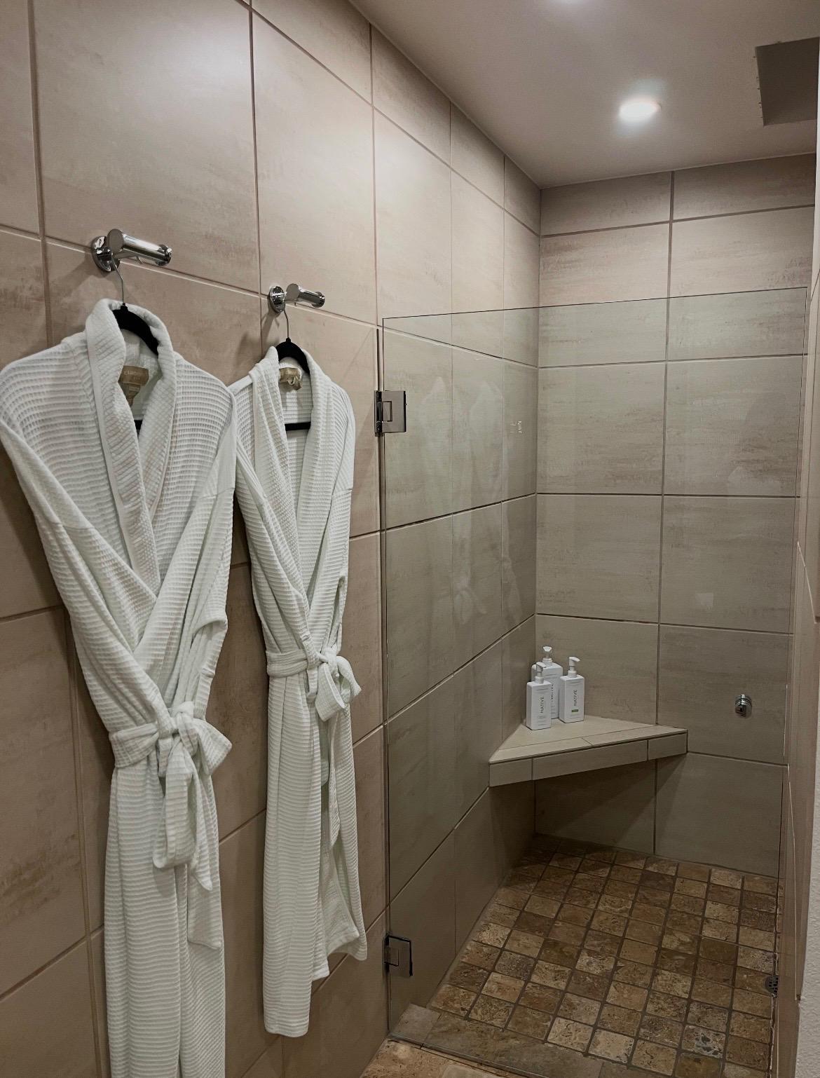 Walk-in shower with robes hung and towels staged after a cleaning