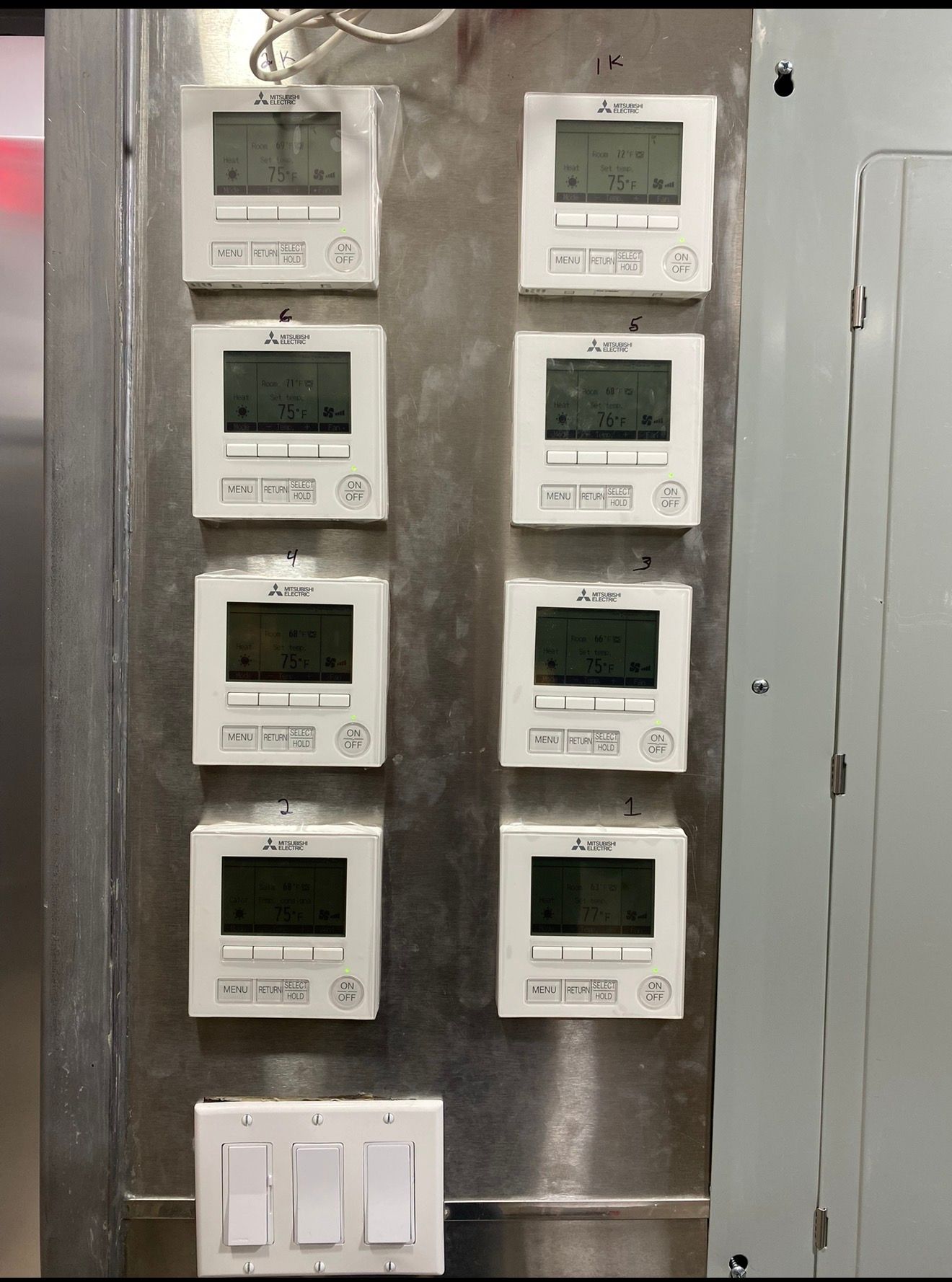 A stainless steel panel fitted with eight zone controllers for a multi-zone commercial system